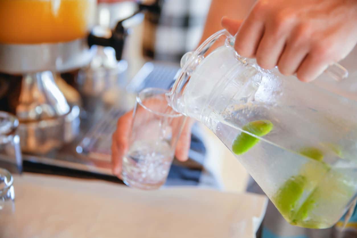 Adult men pouring infused lemon water to drinking glass