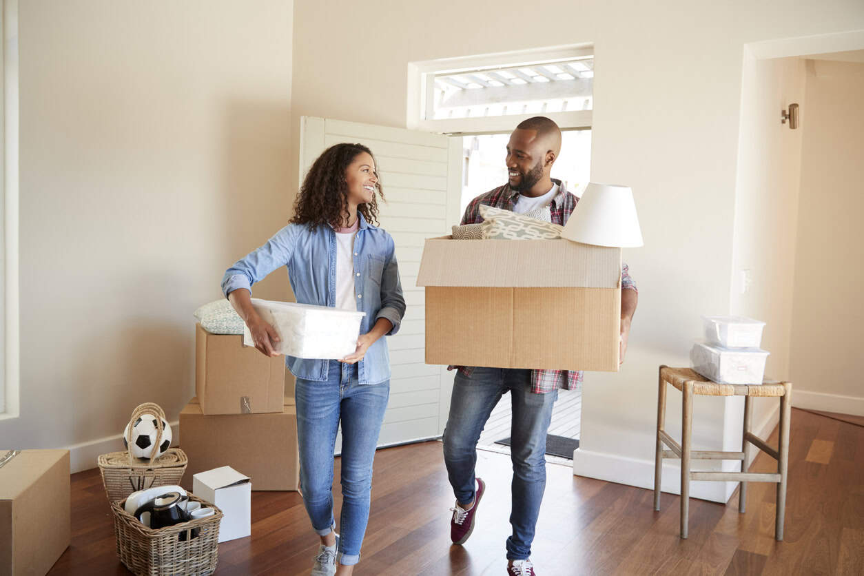 A couple carrying boxes into their new home