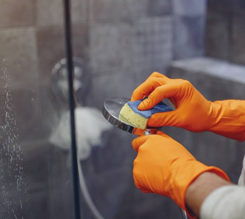 A man cleaning a dirty showerhead from hard water build up.