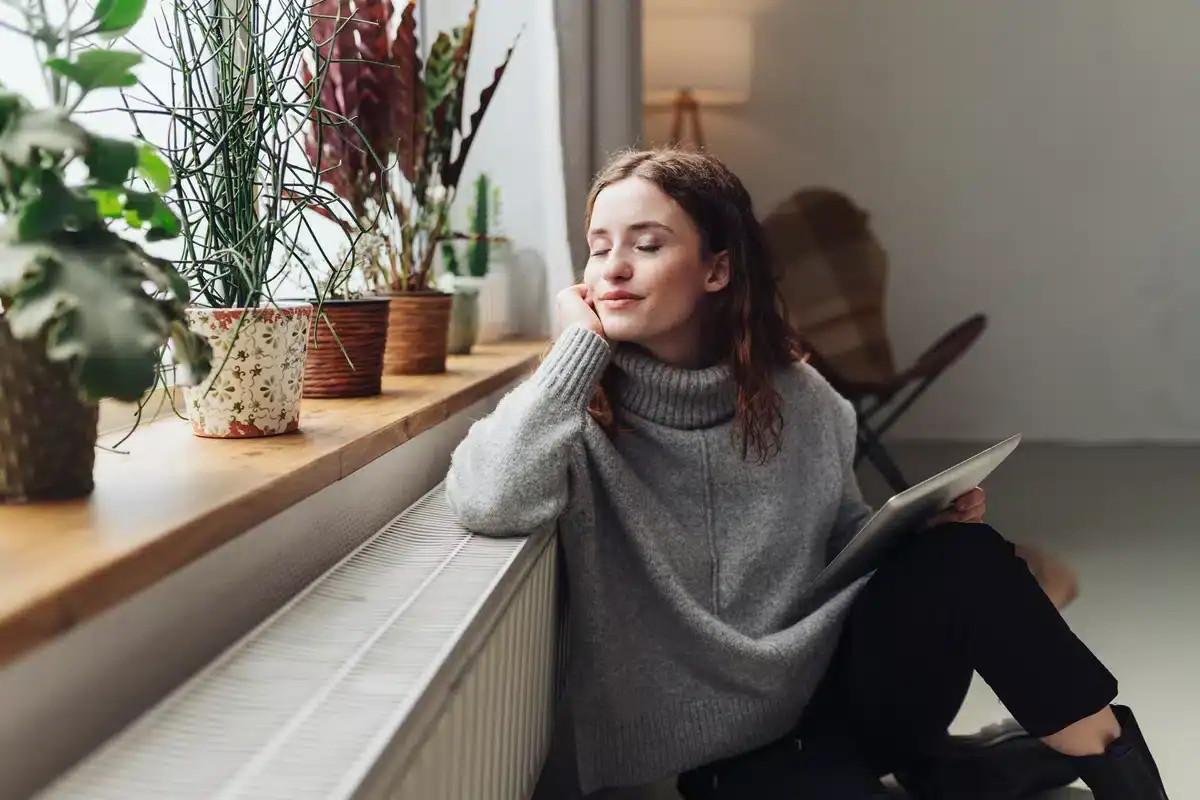 a woman sits by her heater