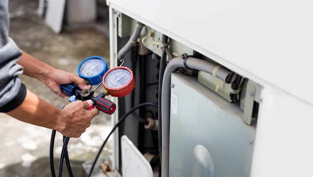 Air Repair Mechanic Using Measuring Equipment For Filling Industrial Factory Air Conditioners.