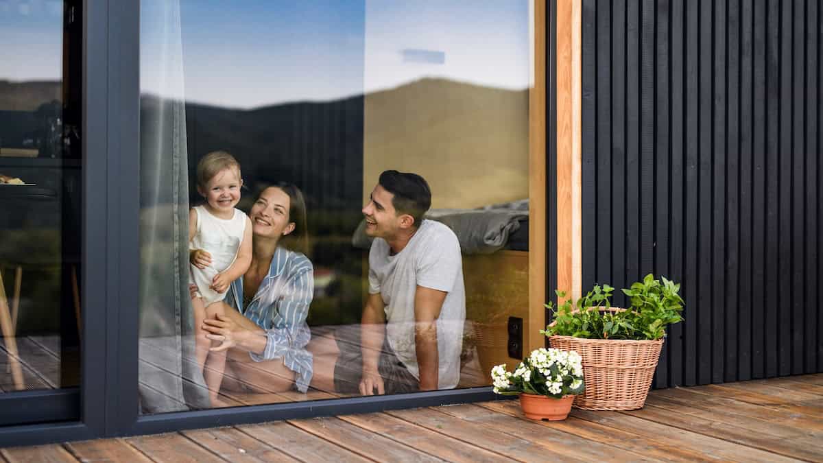 Young Family With Small Daughter Indoors, Weekend Away In Container House In Countryside.