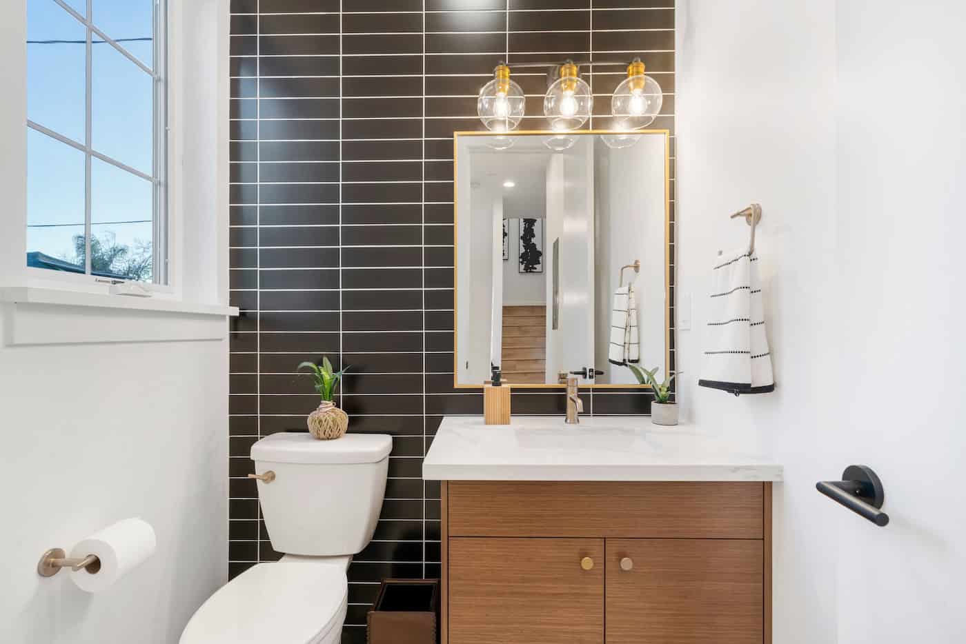 Modern Bathroom With Black Subway Tiles Running Parallel  Along The Back Side Of The Wall Including Gold Accents