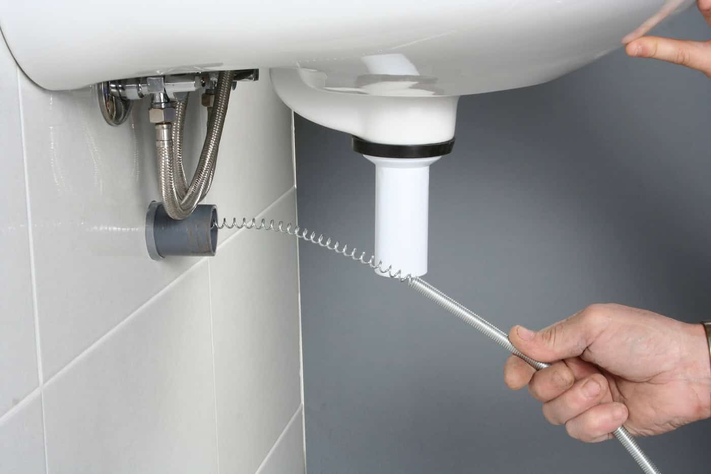 Plumber Using A Drain Snake To Unclog A Sink...