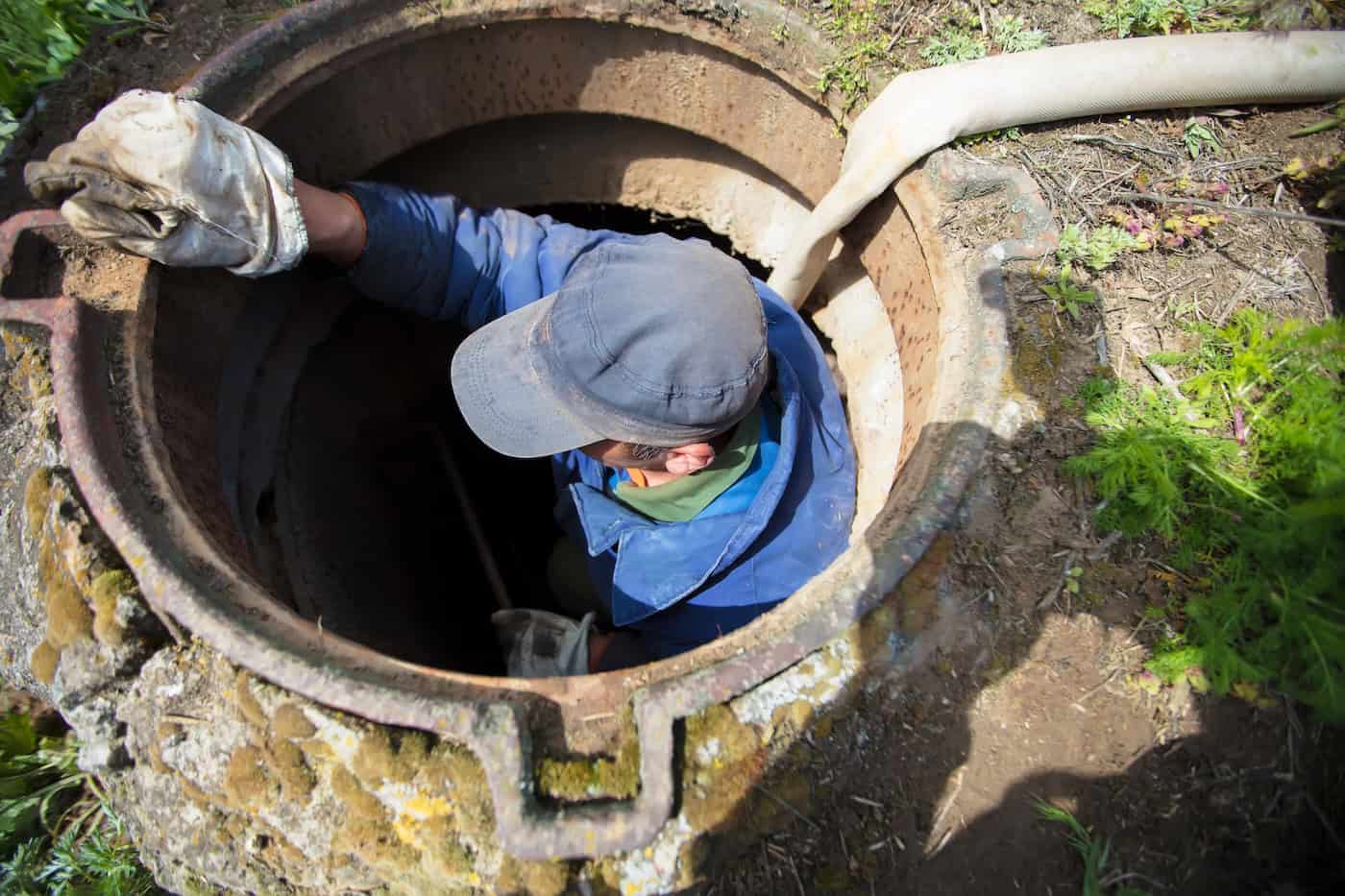 Worker Cleans The Sewer Hatch.a Worker Cleans A Sewer Hatch. A Man In The Hatch.