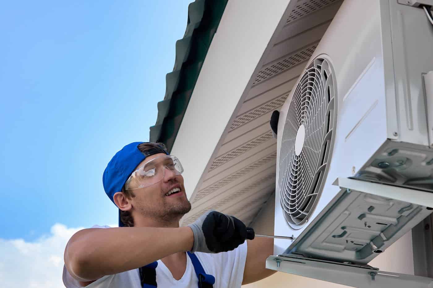 Against Background Blue Sky, Qualified Electrician Installs An Air Conditioner