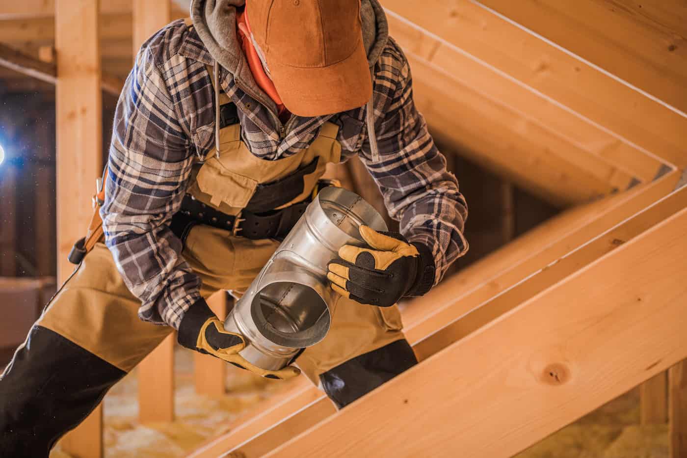 Male Contractor Assembling Hvac Pipes In Attic Of New House.