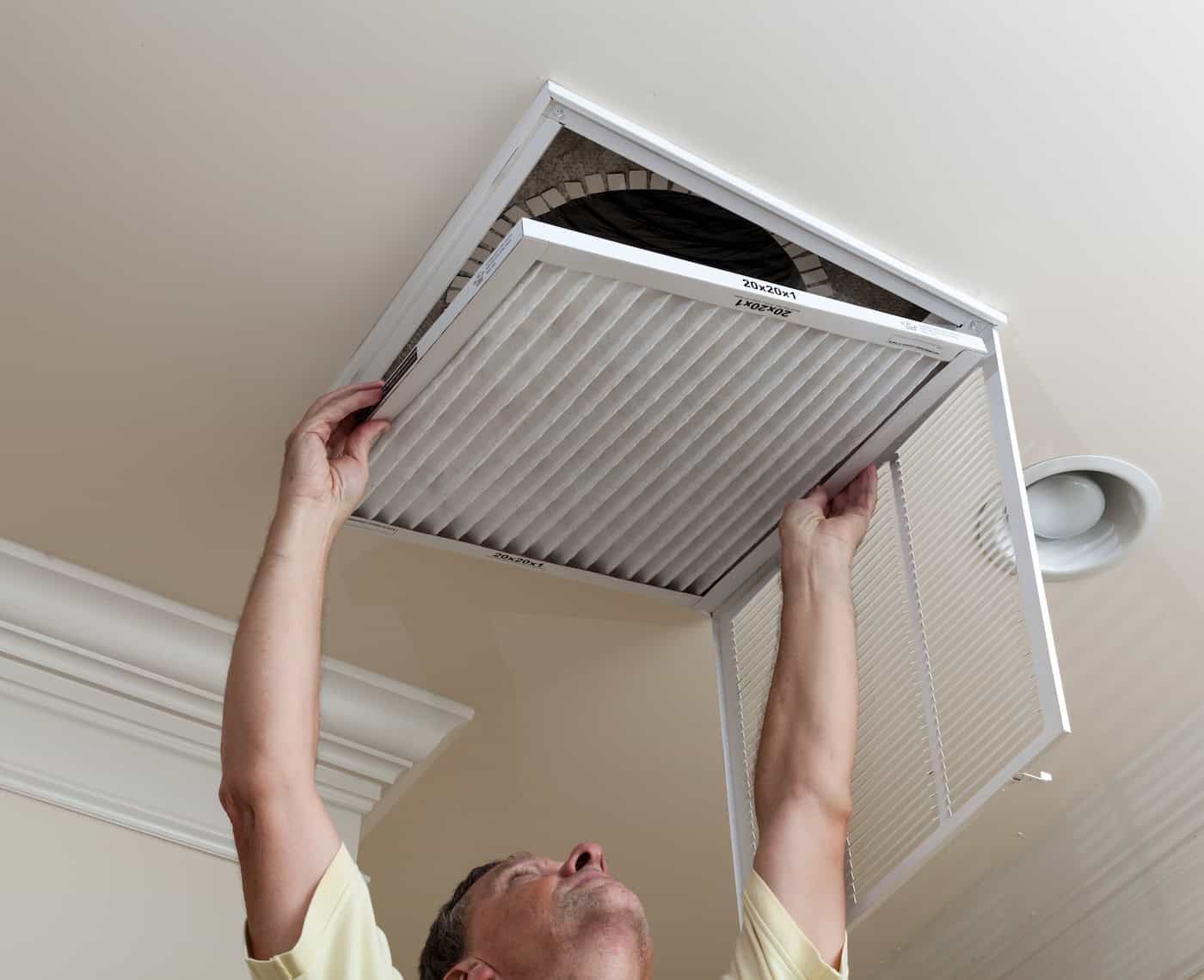 Senior Man Opening Air Conditioning Filter In Ceiling