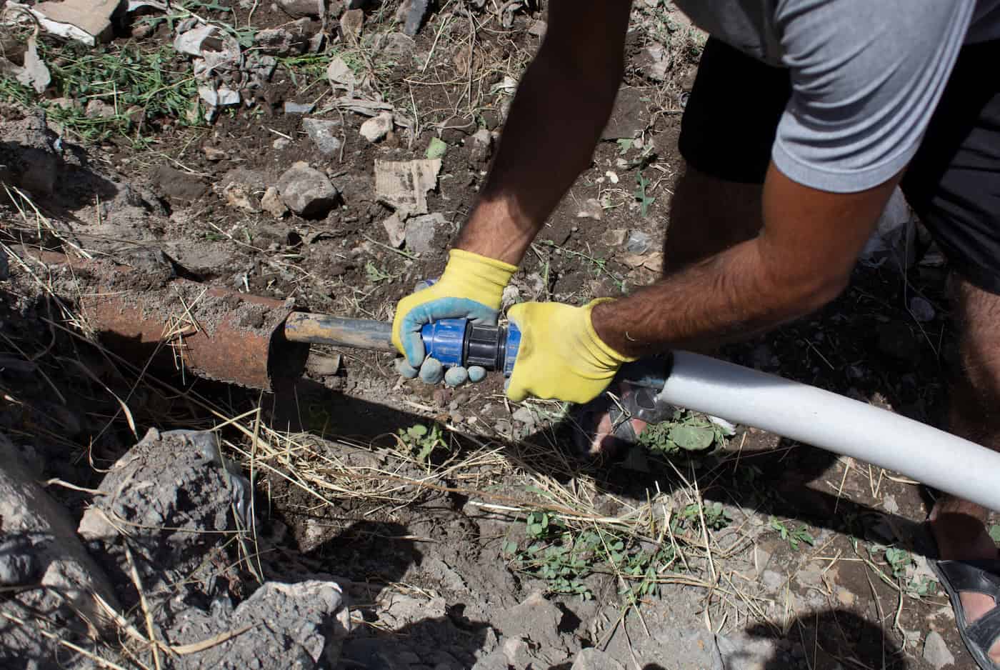Plumber Connects A Water Pipe In A Trench