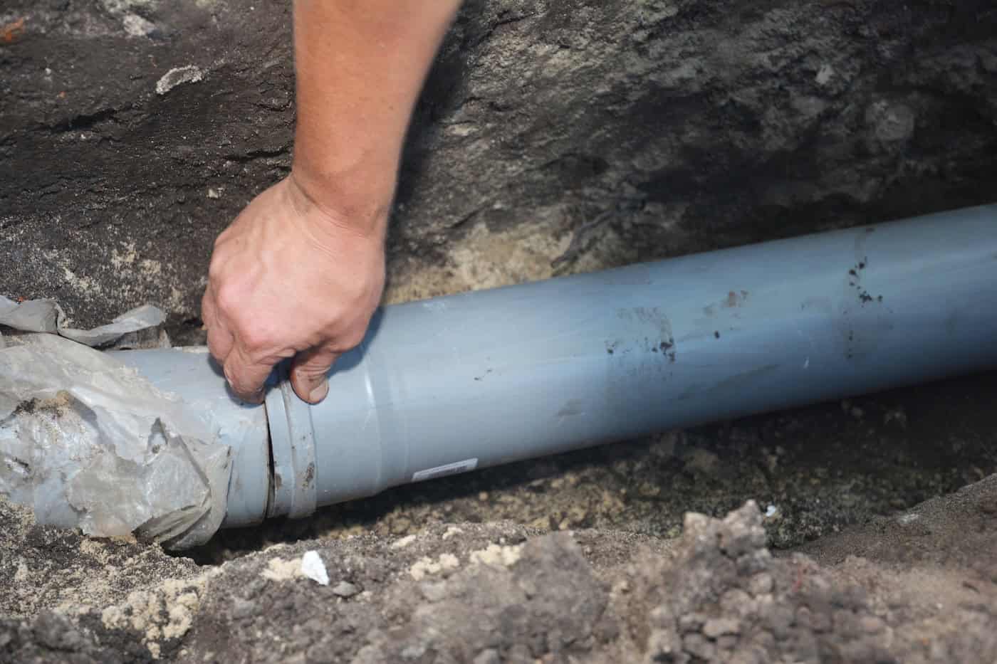 Contractor Installing House Sewer Pipe In The Ground Trench