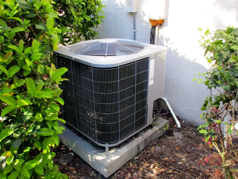 AC unit outside behind a bush