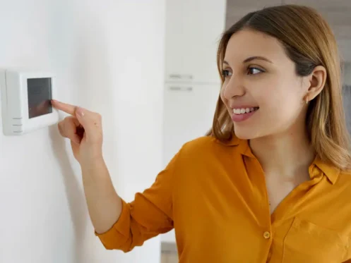 Smiling woman adjusting a thermostat