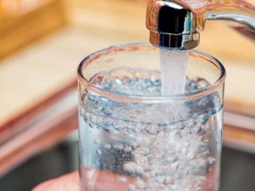 Person filling up a water glass with tap water