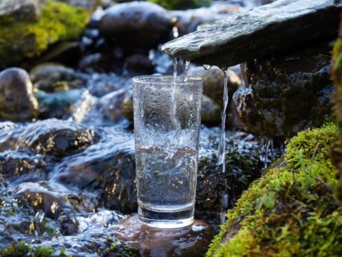 Glass getting filled with water from a river