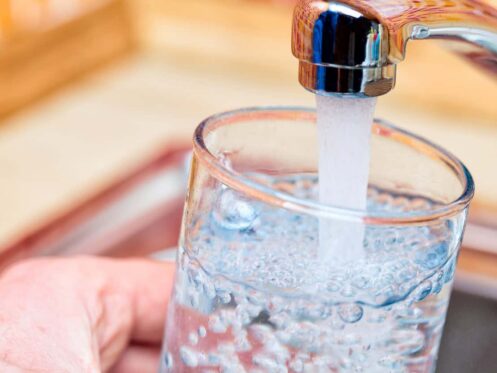 Person filling up a water glass with tap water